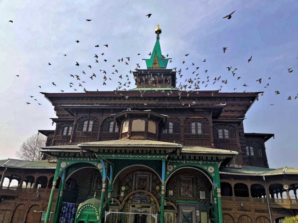 Pigeons flying over a mosque in Srinagar on Kashmir tour by Eka Experiences