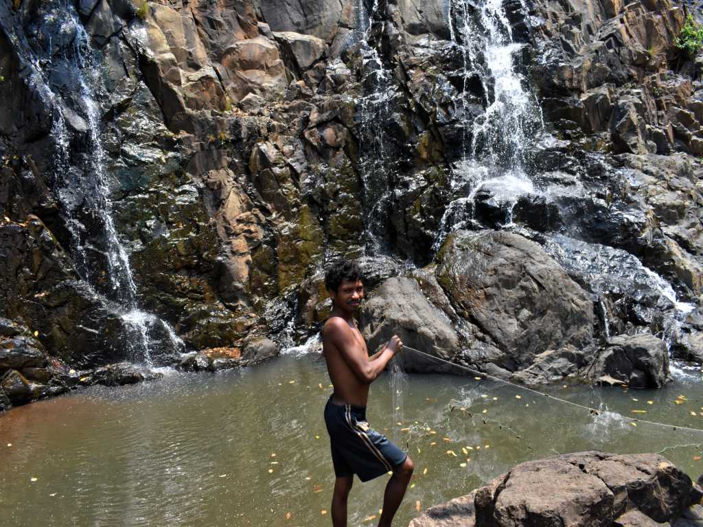 Tribal villager fishing with net in a waterfall