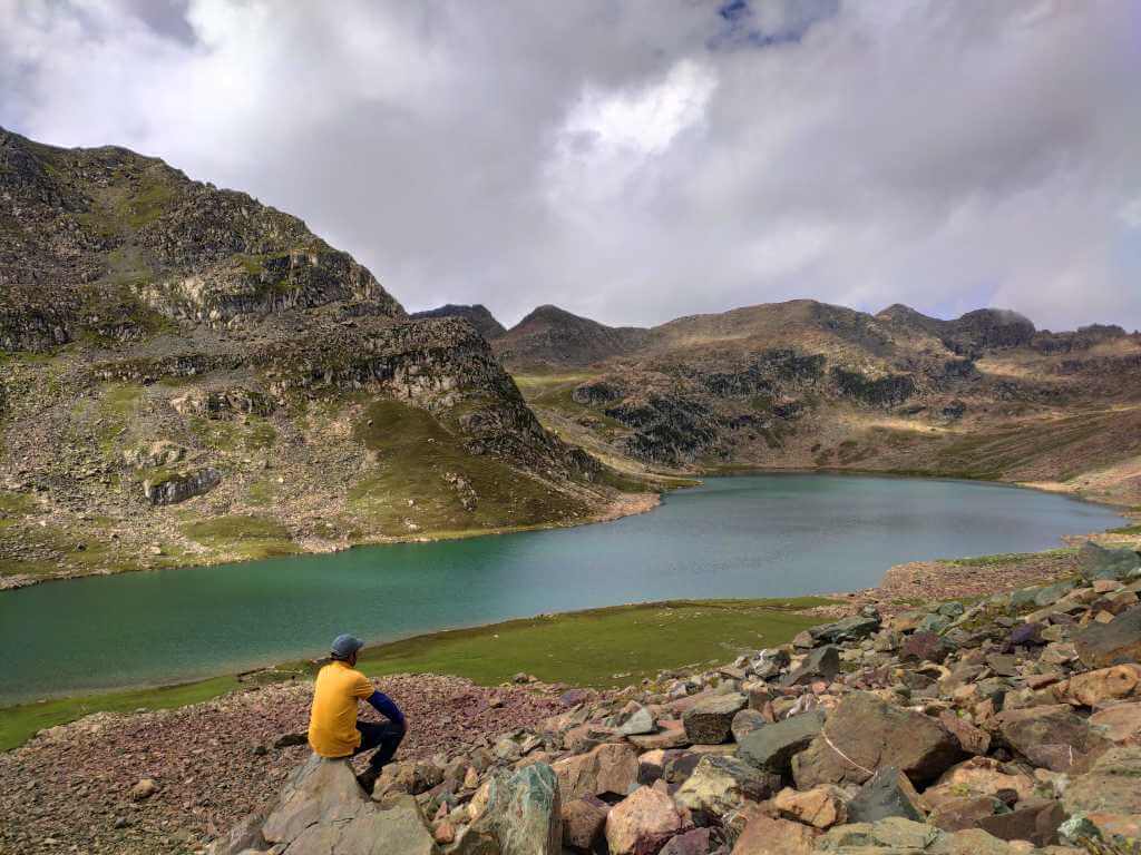 Person sitting on rock and admiring the Patalwan lake views_Gurez Valley Trek